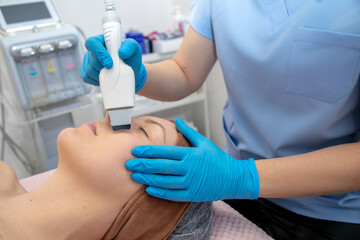 Unrecognizable cosmetologist hands in gloves using hydra facial peel machine hand piece to patient face skin. Face care