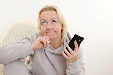 thinking dreaming beautiful woman posing using mobile phone Female standing pose on isolated white background woman typing on mobile phone holding mobile phone and looking away with hand on her chin 