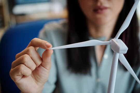 Closeup image of woman touching blate of small plastic wind turbine