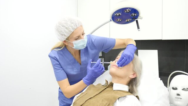 Senior woman recieving botulinotherapy during doctor's appointment in cosmetological clinic.