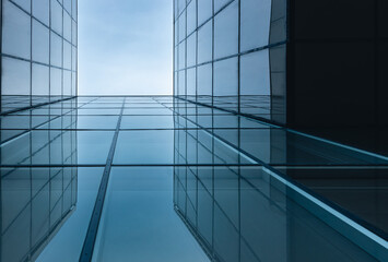 The blue sky is reflected in the windows of a modern office building. Architecture and exterior of contemporary houses