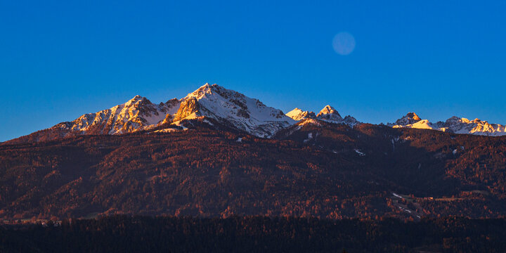 Sunrise over the Alps Mountains Northern Range, snow-covered peak skyline and the blue sky over the village houses in Tyrol, western Austria, tranquil majestic nature landscape