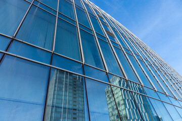 Fototapeta na wymiar The blue sky is reflected in the windows of a modern office building. Architecture and exterior of contemporary houses