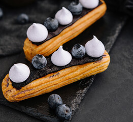 Beautiful and tasty eclairs on a slate board with petals