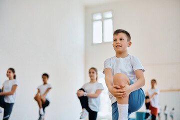 Happy student and his classmates practicing on PE class at school gym.