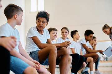 Fototapeta premium Multiracial group of elementary students talk during physical education class at school.
