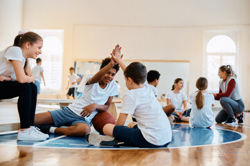 Happy boys giving high five on PE class at school gym.