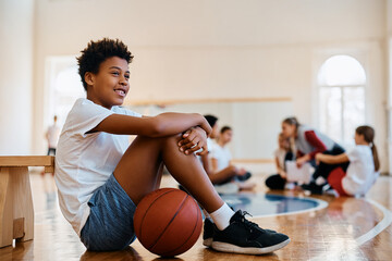 Happy African American student relaxing on floor during PE class at school.