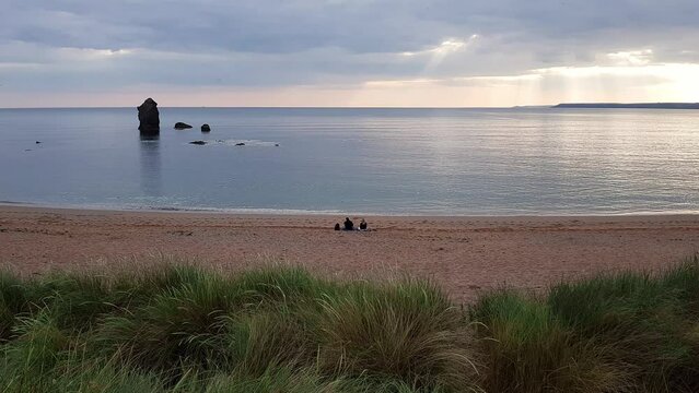 Young couple and dog enjoying the peaceful scenic landscape of South Milton Sands, South Devon, just before sunset