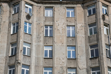 Obraz premium Old gray apartment block wearing the sign of world war II in Warschau. Damaged, old, soviet style, ugly