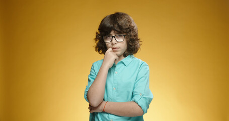 Little caucasian boy looking at camera in misunderstanding, isolated on yellow background - emotions concept close up