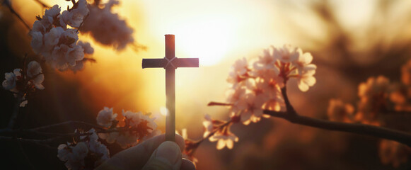 Background with red sunset and spring cherry blossoms and Christian holding the Holy Cross of Jesus...