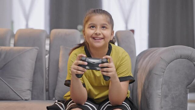 Happy Indian gamer kid playing video games using controller