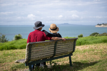 Couple enjoying the stunning views of Hauraki Gulf with Rangitoto Island in the distance. Long Bay Coastal Walkway. Auckland.