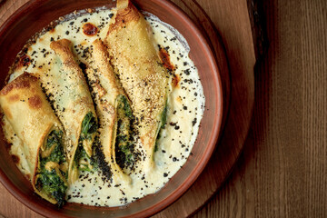 Pancakes with spinach, nuts in a creamy sauce. Ukrainian cuisine Blini or mlynets.