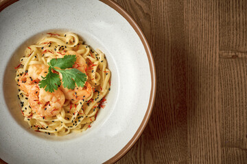 Thai noodles with shrimps in a plate on a wooden background