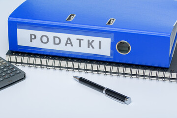 Niebieski segregator z fakturami firmowymi leżący na kołonotatniku na biurku w pracy