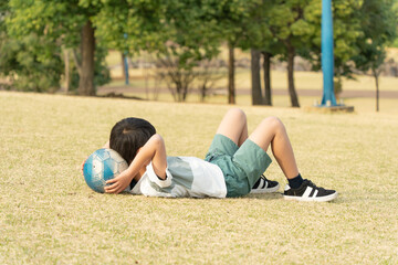 Fototapeta premium 芝生で寝そべる小学生の男の子