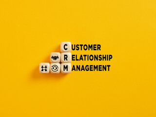The acronym CRM and Customer Relationship Management text on wooden cubes on yellow background.