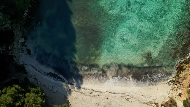 Shadows cast over beach along Menorca's coastline in Spain at sunset.