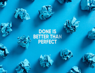 Done is better than perfect message with crumpled blue paper balls on blue background.