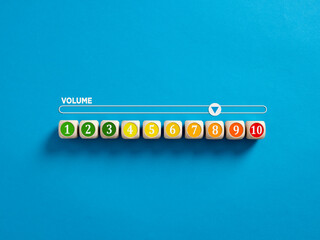 Volume level numbers on wooden cubes with a volume meter on blue background.