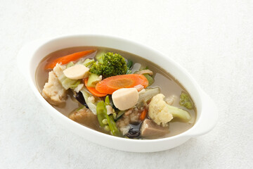 Capcay, stir fried vegetables with shrimp, meatballs and chicken. Served in white plate

