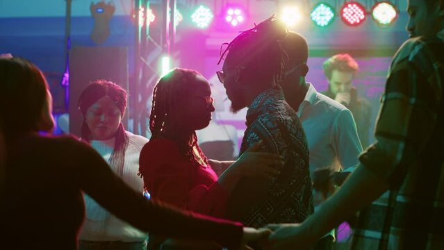 Happy couple dancing on slow music, enjoying romantic moment on dance floor. Dance partners having fun with slow waltz at nightclub, partying together at social gathering. Tripod shot.