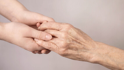 The hand of a young girl reaches for an old hand. Help for the elderly.