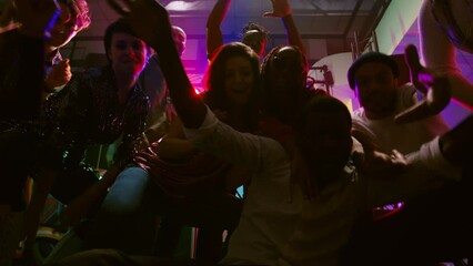 POV of young people dancing at party, showing funky dance moves on camera at discotheque. Group of men and women partying on clubbing music at nightclub, having fun. Handheld shot.