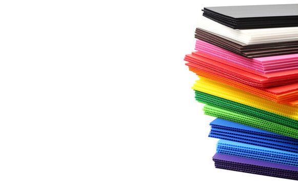 Stack of colorful corrugated plastic sheets isolated on white background with space on left