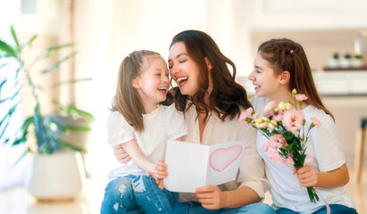 Daughters giving mother bouquet of flowers.