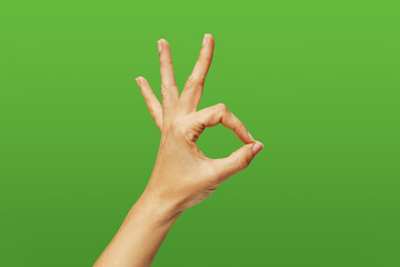 woman's hand making the ok sign, on green background