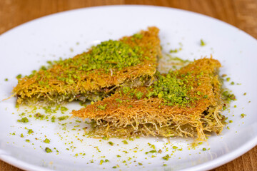 Pistachio kadayif. Turkish cuisine sherbet desserts. Kadayif dessert with pistachio on wood...