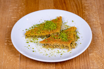 Pistachio kadayif. Turkish cuisine sherbet desserts. Kadayif dessert with pistachio on wood background.