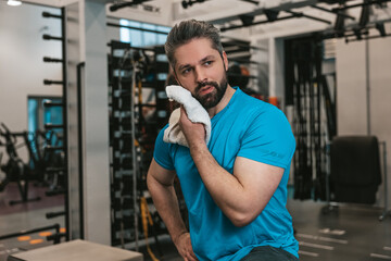 Young man wiping sweat with the towel after workout