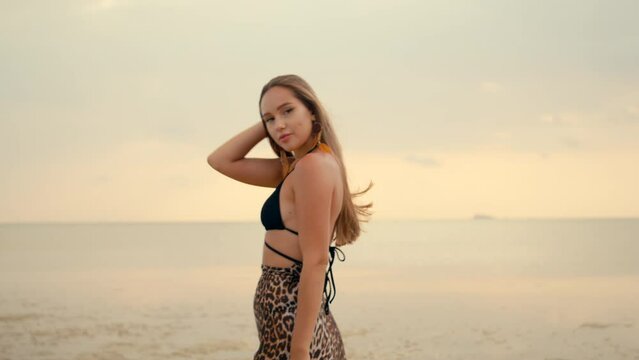 Beautiful long-haired girl walks on the beach at sunset. Anamorphic shot
