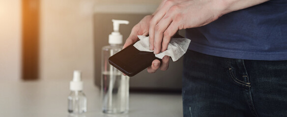 Man disinfecting phone with antiseptic wet wipe