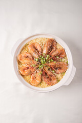 poached fried jasmine rice with giant tiger sea prawn and green bean vegetable in yellow golden chicken stock cheesy sauce in claypot on wood table asian chinese halal food seafood menu for restaurant