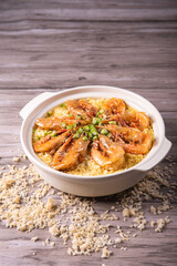 poached fried jasmine rice with giant tiger sea prawn and green bean vegetable in yellow golden chicken stock cheesy sauce in claypot on wood table asian chinese halal food seafood menu for restaurant