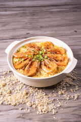 poached fried jasmine rice with giant tiger sea prawn and green bean vegetable in yellow golden chicken stock cheesy sauce in claypot on wood table asian chinese halal food seafood menu for restaurant