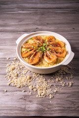 poached fried jasmine rice with giant tiger sea prawn and green bean vegetable in yellow golden chicken stock cheesy sauce in claypot on wood table asian chinese halal food seafood menu for restaurant