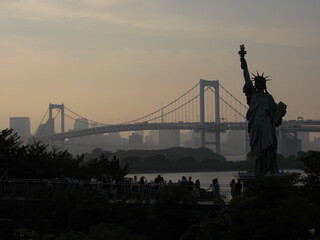 Statue of Liberty and Rainbow Bridge at sunset in Odaiba
