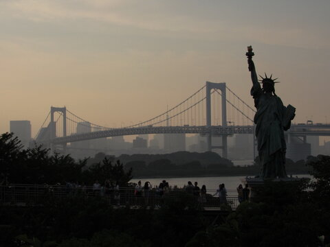Statue of Liberty and Rainbow Bridge at sunset in Odaiba