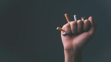 Hands clenched to crush cigarettes. Black background. Health care concept to avoid health hazards.