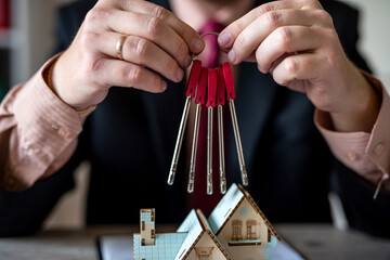 man signs  contract based on an architectural model of a house holds keys to house in his hands