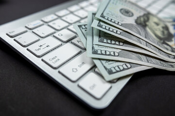 white computer keyboard on which a large sum of dollars is laid out close by limply isolated.