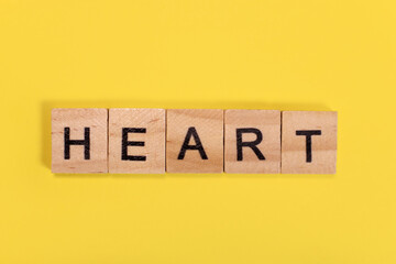 Heart word from wooden letters on yellow background