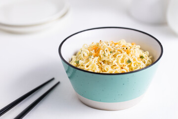 A Turquoise Bowl Filled with Instant Noodles on White and Bright Background 