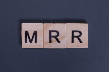 MRR short for Monthly Recurring Revenue from wooden letters on a gray background